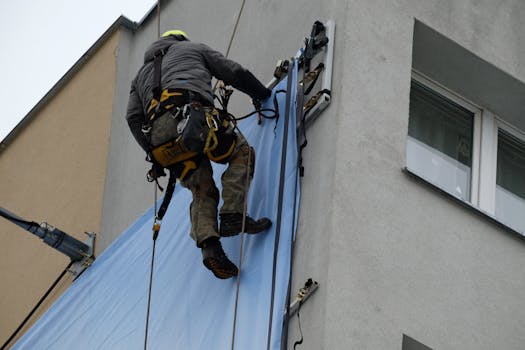 A construction worker on a high-rise building securing a large banner, showcasing industrial work.